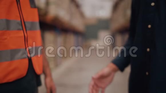 一名经理和工人在模糊的仓库用品背景下握手的中镜头视频的预览图