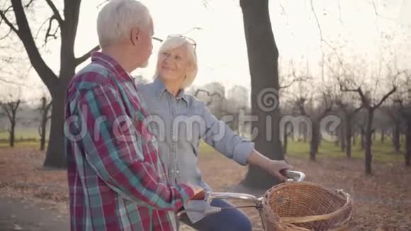 快乐的高白种人女人站在秋天的公园里看着她可爱的丈夫成熟的退休夫妇视频的预览图