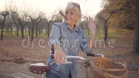 积极成熟的白种人女士穿着休闲服装站着自行车对着镜头挥手美丽的欧洲退休视频的预览图