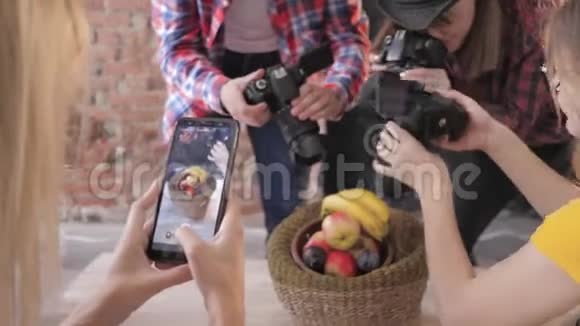 现代的经营者使用照相机和手机在主人的餐桌上拍摄篮子里的水果视频的预览图