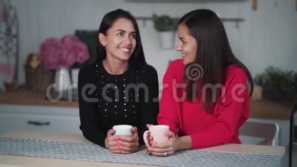 两个年轻的女朋友晚上在厨房喝茶聊天玩得开心视频的预览图