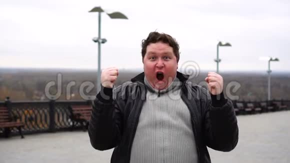 放大快乐的肖像惊讶的胖子直视镜头表达他赢得了什么视频的预览图