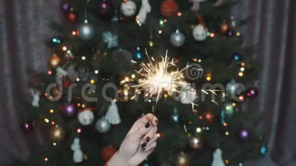 一个女孩在圣诞树的背景下拿着一个闪闪发光的东西视频的预览图
