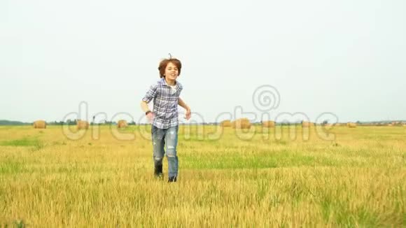 在村里的干草堆背景下微笑的男孩少年跑在收割场上快乐的少年奔跑视频的预览图