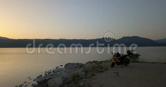 一辆摩托车停在一个巨大的湖面上倒影着夕阳4K视频的预览图
