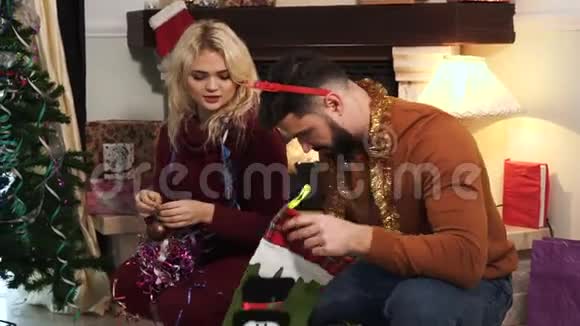 为家里的圣诞树挑选装饰品的白种人年轻人的特写镜头夫妻装修视频的预览图