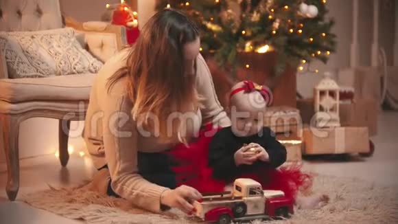圣诞节一个女人和她的小女儿玩圣诞球和玩具车视频的预览图