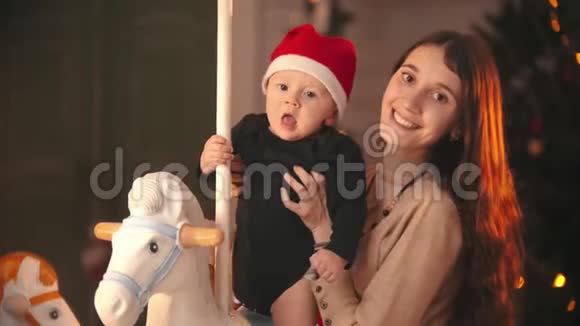 圣诞节概念一位年轻的母亲带着她的孩子看着镜头婴儿坐在旋转木马上视频的预览图
