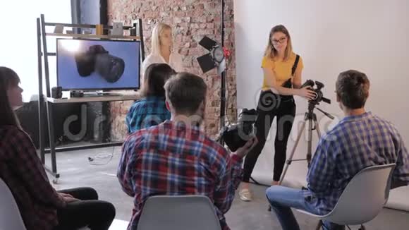 专业摄影师帮助年轻人在摄影学校学习摄影时把镜头放在单反相机上视频的预览图