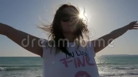 年轻女子在海边享受着温暖的风站在岸边回到水面上对着太阳画像视频的预览图