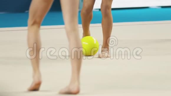 年轻女子在艺术体操比赛中的腿穿着泳装的女孩停止了球并把球举起来视频的预览图