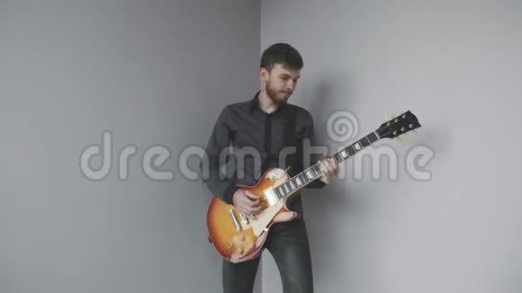 英俊的白种人摇滚吉他手胡子和灰色衬衫演奏电吉他孤立有魅力的男吉他演奏者当选视频的预览图