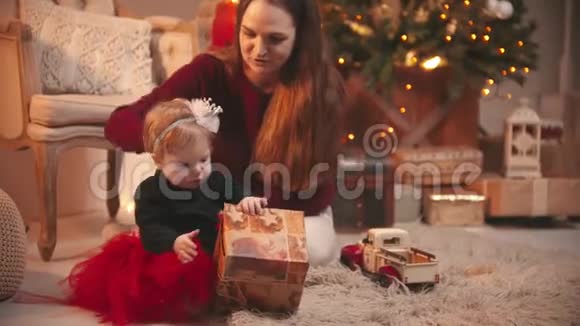 圣诞节概念一个女人和她的小女儿坐在工作室里玩礼物盒视频的预览图