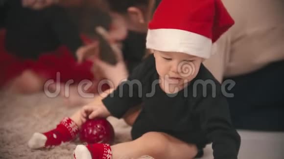工作室里的圣诞装饰品小男孩和小女孩在地毯上玩玩具视频的预览图
