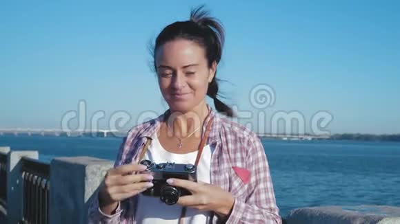美丽的女人在河岸和微笑的复古摄影镜头上拍照视频的预览图