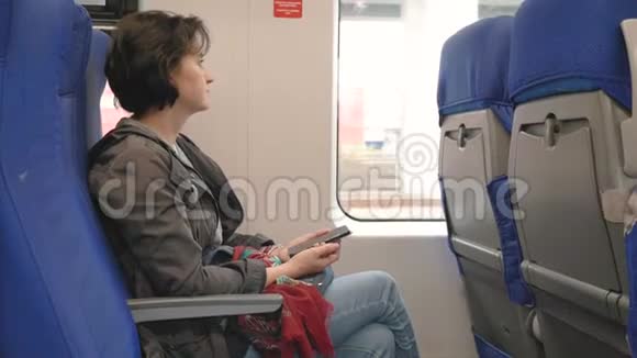 乘火车靠窗白种人女人拿着智能手机看窗外视频的预览图