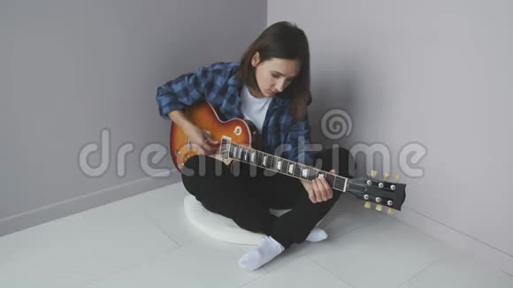 年轻可爱的女人坐在地板上弹电吉他练习音乐会漂亮的女人用电吉他弹奏蓝色视频的预览图