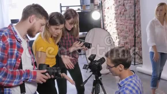 专业摄影工作室的摄影师工作室正在培训年轻的摄影师在后台安装数码相机视频的预览图