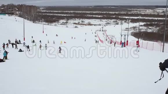 人们在冬季滑雪场的雪坡上滑雪和滑雪板雪山上的滑雪电梯冬季活动视频的预览图