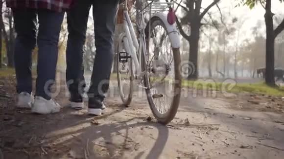 在公园的小巷里两双成年腿穿着运动鞋骑着自行车行走家庭或朋友视频的预览图