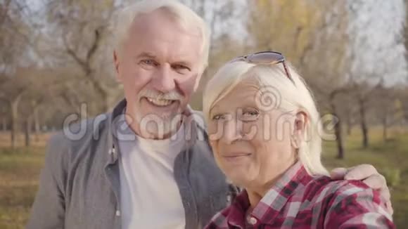 微笑的白种人退休夫妇在镜头前挥手的特写照片成熟的欧洲家庭站在阳光下视频的预览图