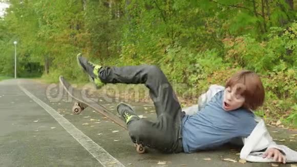 夏天公园柏油路上滑板上的男孩城市公园柏油路上的滑板运动员视频的预览图