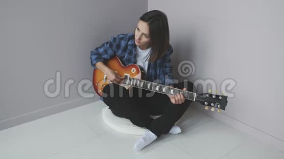 美丽的女性与电吉他演奏和练习摇滚音乐会穿着蓝色衬衫坐在地板上弹吉他的女人视频的预览图