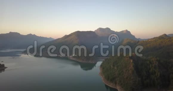 一个有大坝和大山的巨大湖泊的空中镜头五颜六色的日落4k视频的预览图