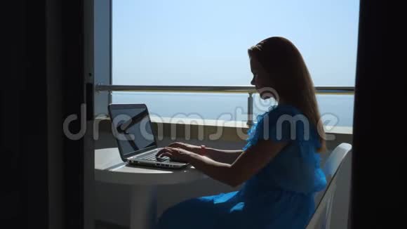 这个女孩在酒店阳台上的笔记本电脑上工作视频的预览图