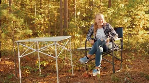 秋天远足时快乐的小女孩在露营地笑着快乐的女孩在秋天公园的周末野餐上开玩笑微笑视频的预览图