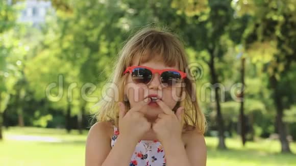 带着太阳镜的有趣的小女孩做鬼脸玩得开心慢动作视频的预览图
