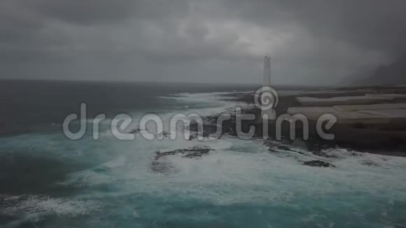 壮观的空中景色在一个巨大的白色灯塔在岩石风暴海岸4k视频的预览图