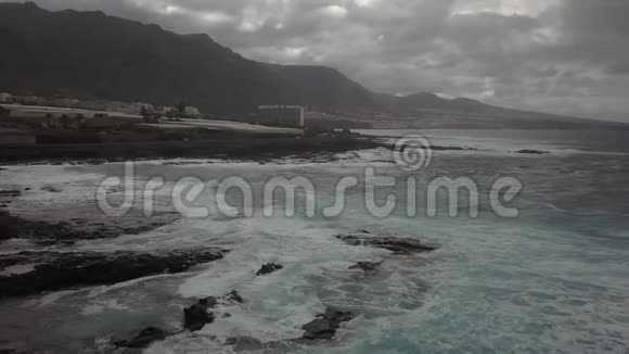 暴风雨的日子里五颜六色的蓝色海水泡沫般的波浪岩石般的海岸4K视频的预览图