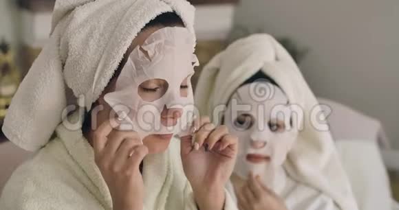 两个成年白种人女人摘下面罩漂亮的女孩穿着发巾和浴袍在家休息电影院4k视频的预览图