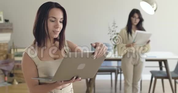 两个年轻的白人女孩用笔记本电脑和文件跳舞后台的女人扔文件视频的预览图