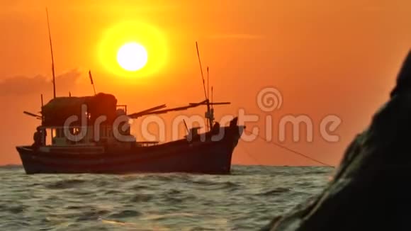 抛锚的渔船在夕阳的光线下在波浪中摆动的剪影视频的预览图