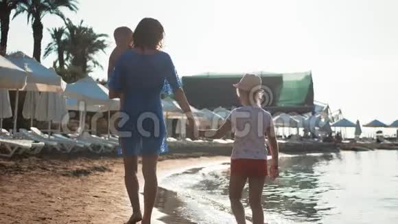 幸福的家庭母亲和两个孩子在海滩度假日落时分母亲和两个孩子在海里视频的预览图