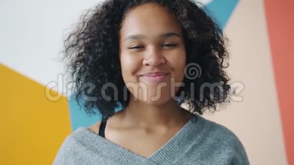 无忧无虑的非裔美国女青年在五彩缤纷的背景下微笑的肖像视频的预览图