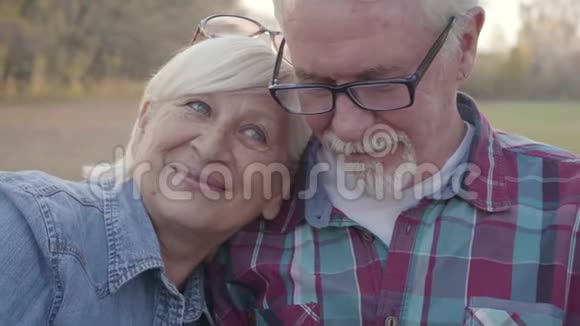 高白种人家庭的特写脸坐在秋天的公园里微笑成熟的欧洲夫妇阳光明媚视频的预览图