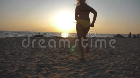可爱的小女孩在热带海滩上奔跑快乐的孩子在美丽的夕阳下奔跑的剪影孩子的脚视频的预览图