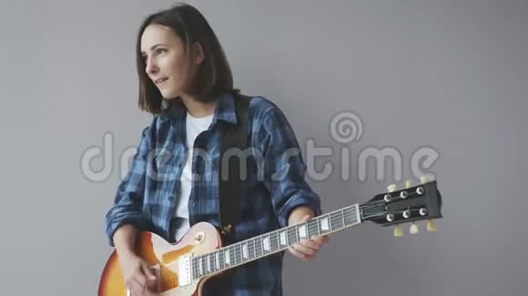 迷人的女孩与电吉他演奏爵士乐和布鲁斯歌曲弹吉他的女性穿着蓝色休闲衬衫视频的预览图