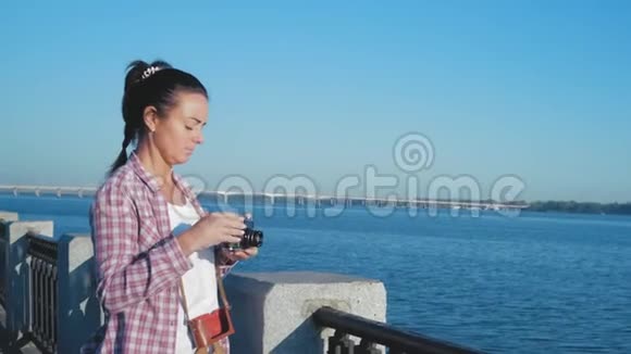 美丽的女人穿着衬衫在河堤的电影摄影机上拍摄景点的照片视频的预览图