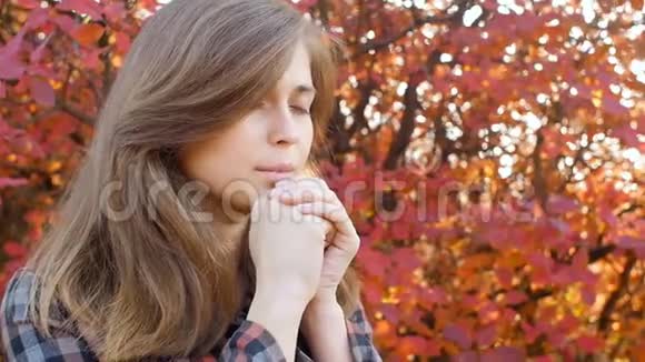 一个美丽的年轻女子的形象感激地仰望着女孩在公园里穿过秋天的自然视频的预览图
