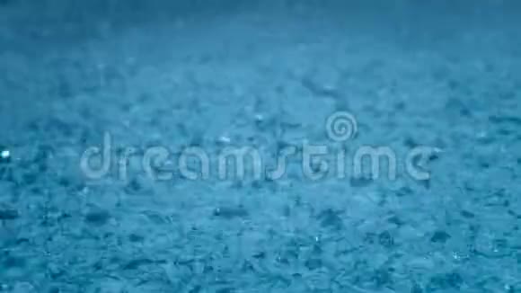 特写雨雨滴落在一个大水坑里雨季视频的预览图