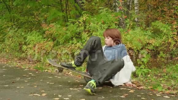 穿休闲服装的少年坐在美丽的公园里的长板上视频的预览图