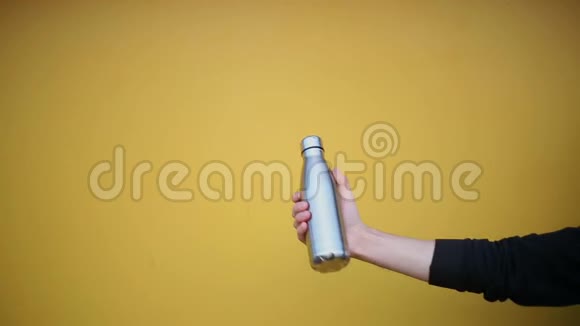 男性手拿一个钢制的生态热瓶用于黄色背景下的水视频的预览图