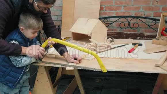 一个小男孩在木制面板上学习使用手锯视频的预览图