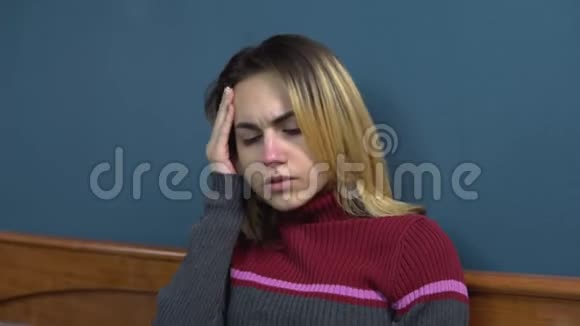 一个年轻的女人吃了一片药头痛那个女孩头痛躺在床上抱着头视频的预览图
