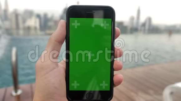 智能手机的特写镜头绿色屏幕彩色键放在游泳池附近在触摸屏上观看视频并跟踪视频的预览图