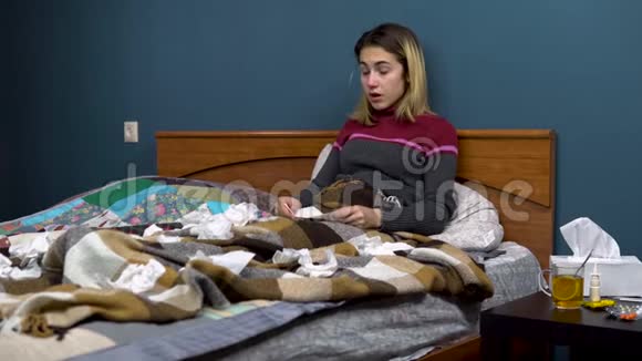 一个年轻的女人打喷嚏用餐巾纸吹鼻子那个女孩躺在床上生病了纸巾散落在周围视频的预览图